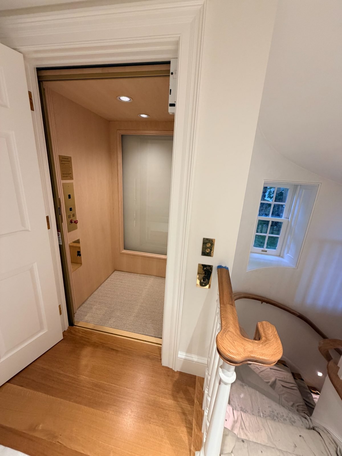 Oak cab with frosted glass panel and carpeted floor at a stair landing