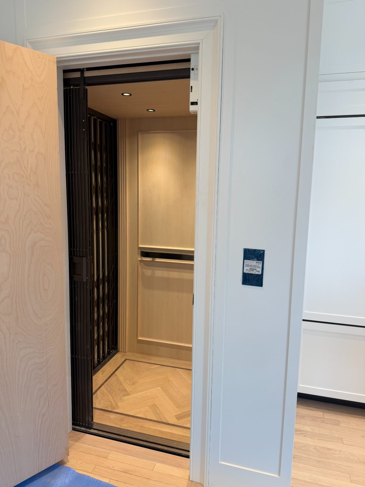 Light-wood cab with bronze accordion gate and herringbone floor
