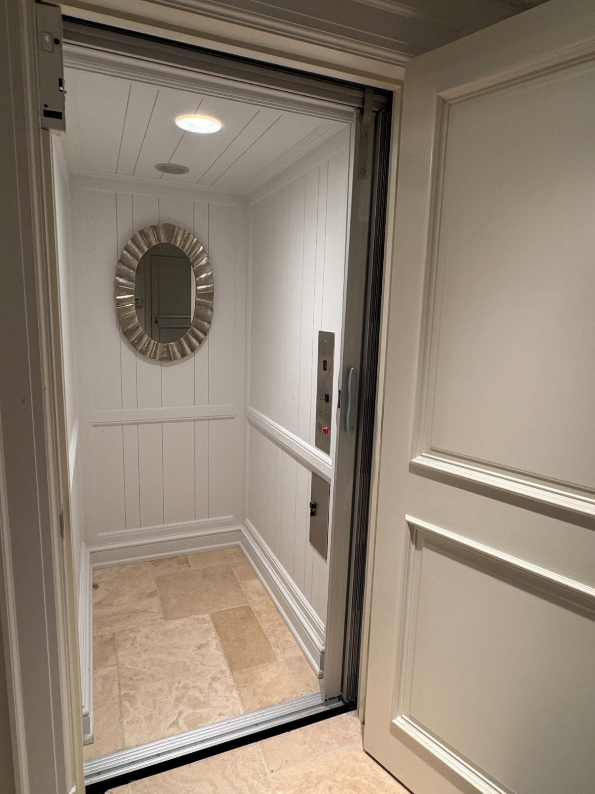 White cab with oval mirror and travertine floor